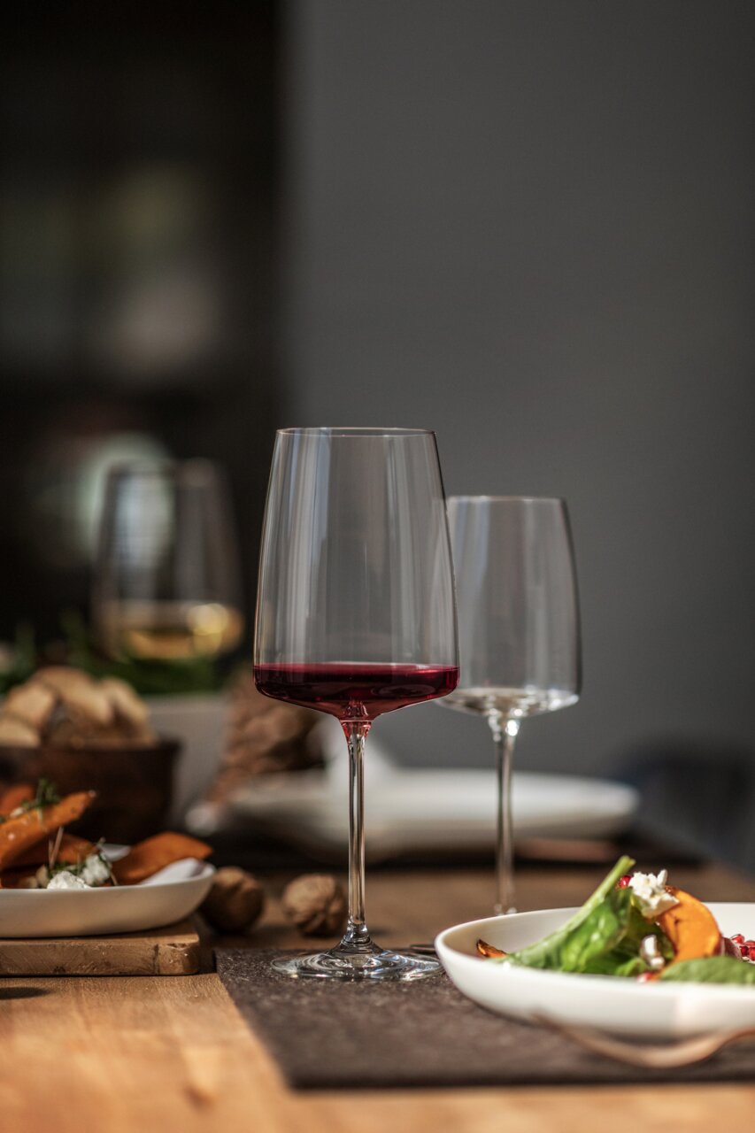 Weinglas mit rotem Wein, auf einem gedeckten Tisch, seitliche Perspektive