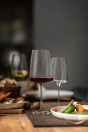 Weinglas mit rotem Wein, auf einem gedeckten Tisch, seitliche Perspektive