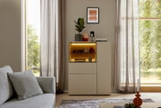 Frontansicht eines modernen beigefarbenen Highboards mit beleuchteter Glasvitrine und dekorativen Wohnaccessoires in einem hellen Wohnzimmer.
