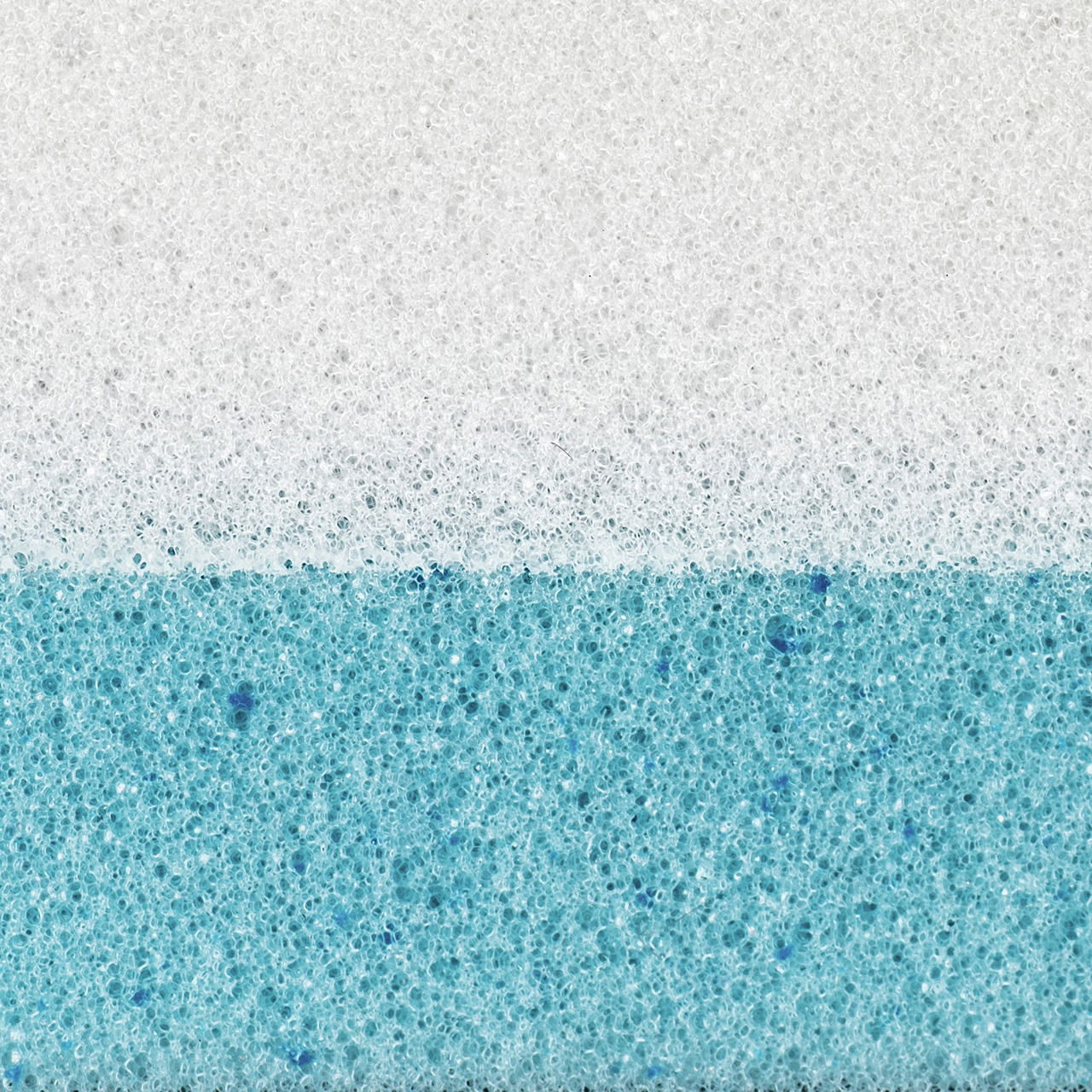 Nahaufnahme eines zweischichtigen Matratzentoppers mit einer weißen und einer blauen Schicht, seitliche Perspektive.