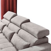 Rückansicht einer grauen Rundecke mit verstellbaren Kopfstützen und roten Vorhängen im Hintergrund.