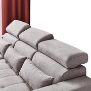 Rückansicht einer grauen Rundecke mit verstellbaren Kopfstützen und roten Vorhängen im Hintergrund.