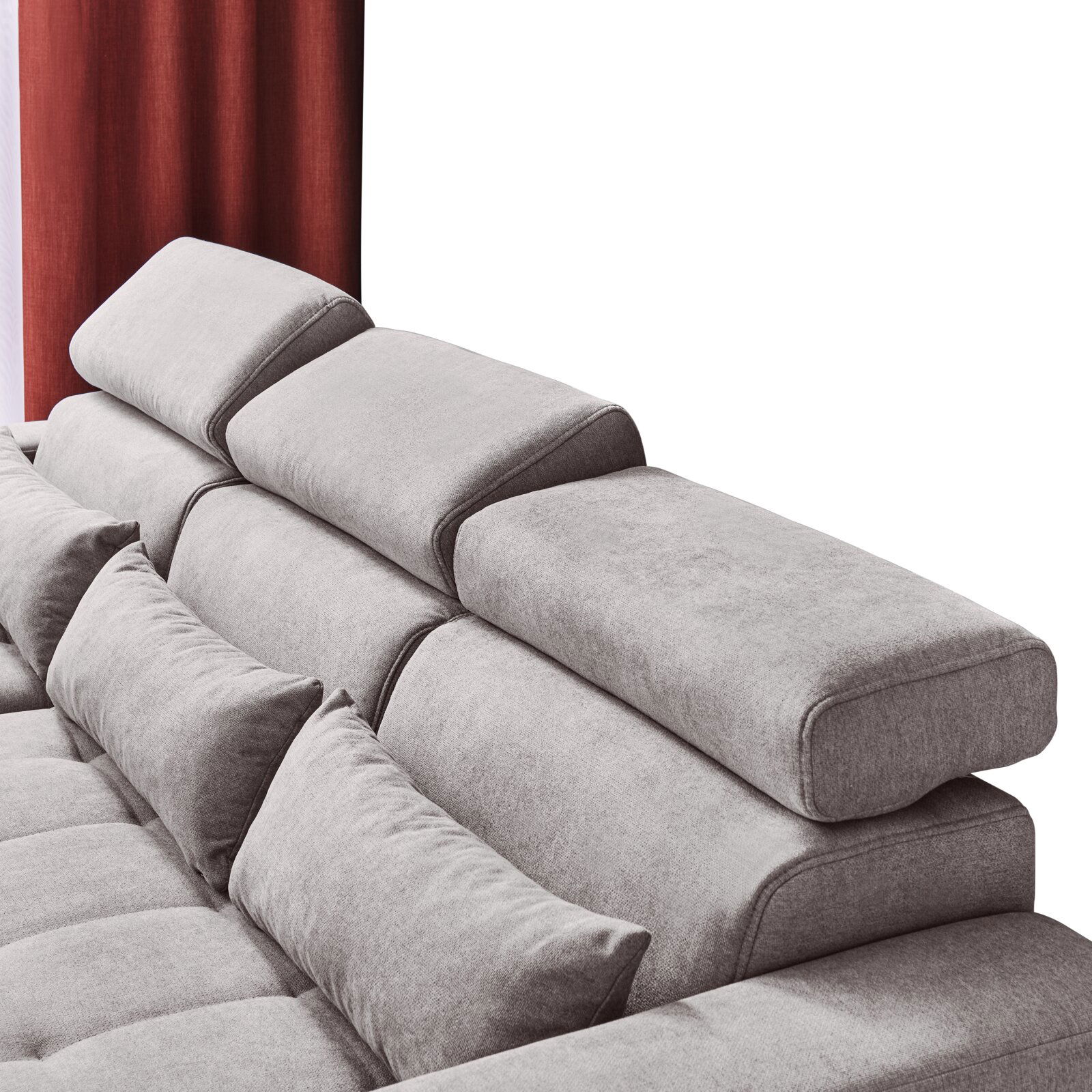 Rückansicht einer grauen Rundecke mit verstellbaren Kopfstützen und roten Vorhängen im Hintergrund.