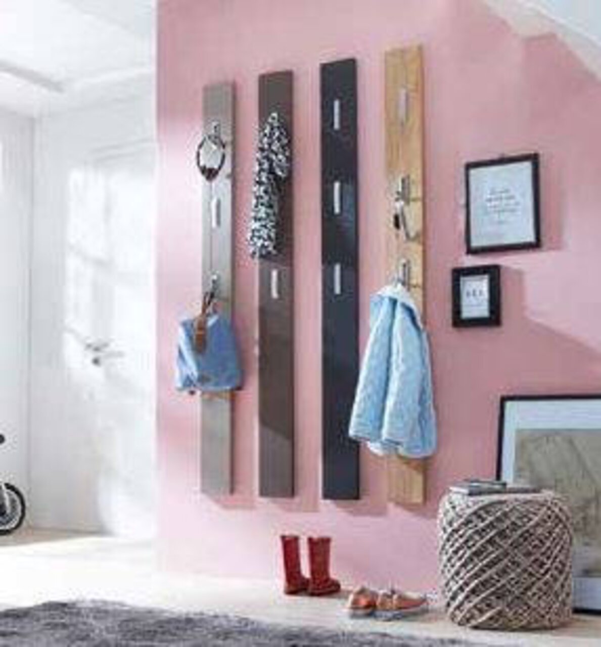 Garderobenpaneel in verschiedenen Farben an einer rosa Wand, frontal betrachtet, mit Kleidung und Accessoires behängt.