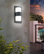 Moderne Wandleuchte 'CISTIERNA' an einer Betonwand, seitliche Perspektive, mit Blick auf einen Balkon bei Sonnenuntergang.