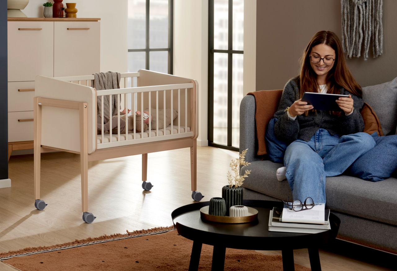 Anstellbett mit Rollen in einem modernen Wohnzimmer, seitliche Perspektive.