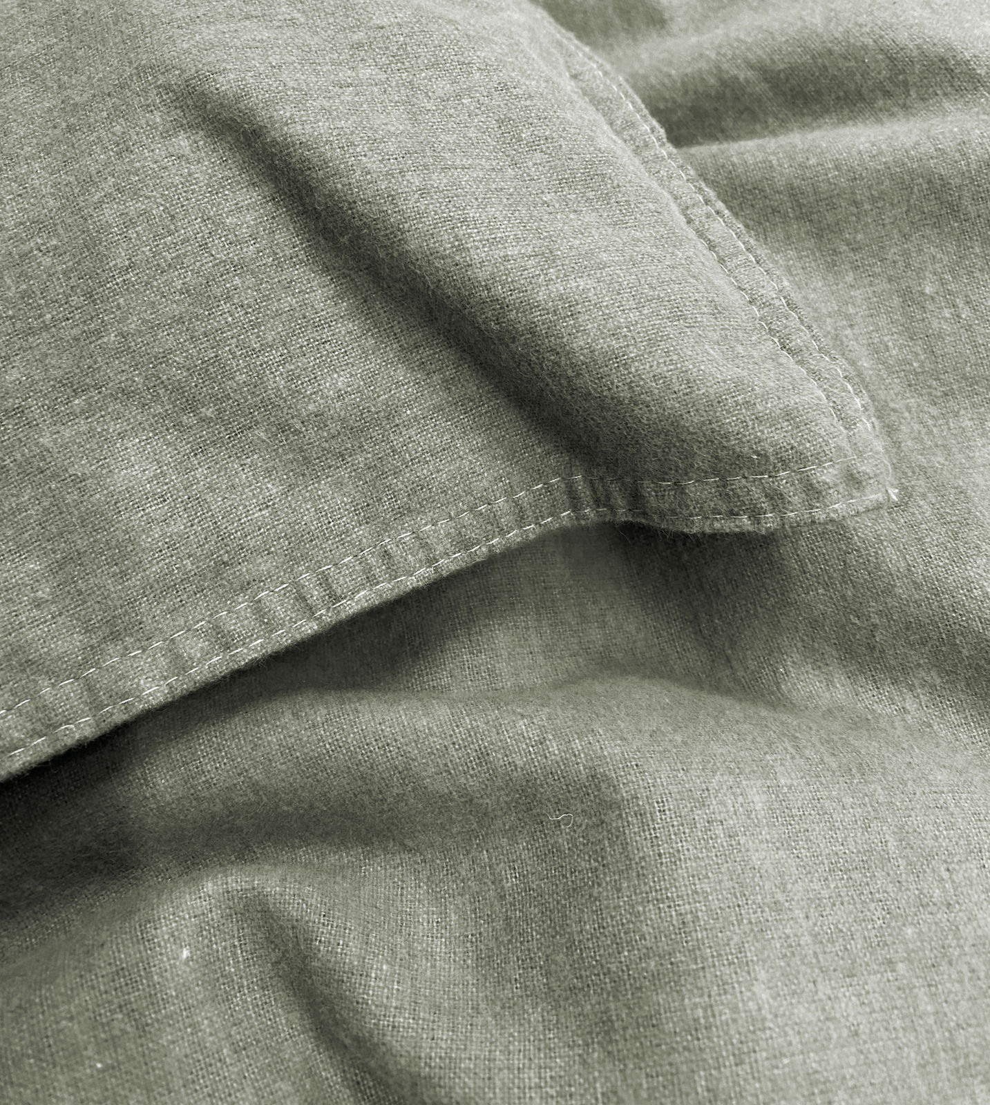 Nahaufnahme von grüner Bettwäsche mit sichtbaren Nähten und Textur
