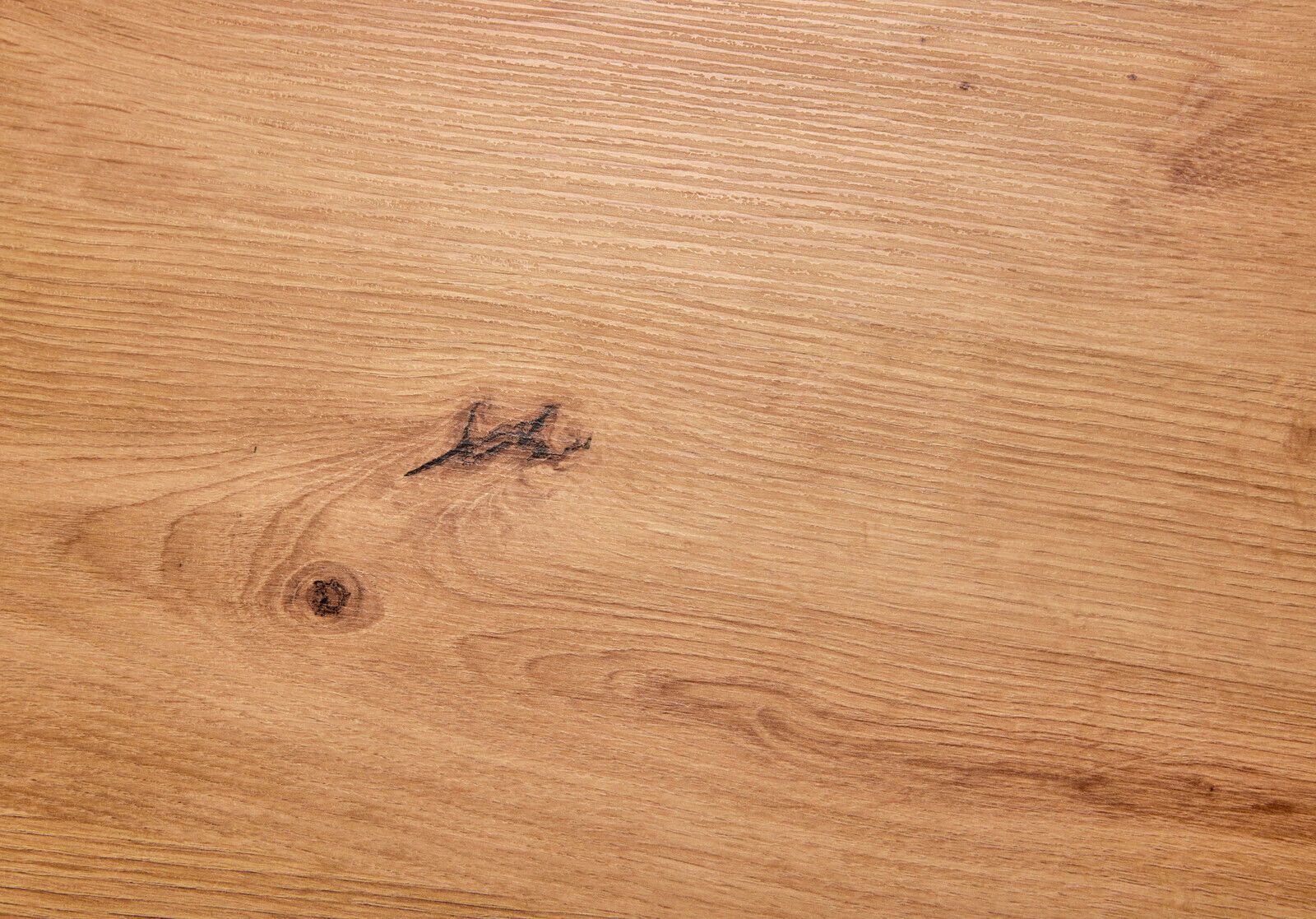 Nahaufnahme einer Holzoberfläche mit natürlicher Maserung und Astloch, von oben betrachtet.