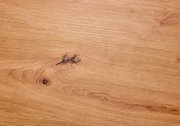 Nahaufnahme einer Holzoberfläche mit natürlicher Maserung und Astloch, von oben betrachtet.