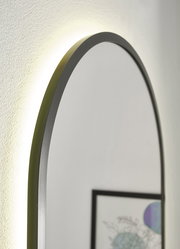 Nahaufnahme eines ovalen Spiegels mit schwarzem Rahmen und Hintergrundbeleuchtung, seitliche Perspektive