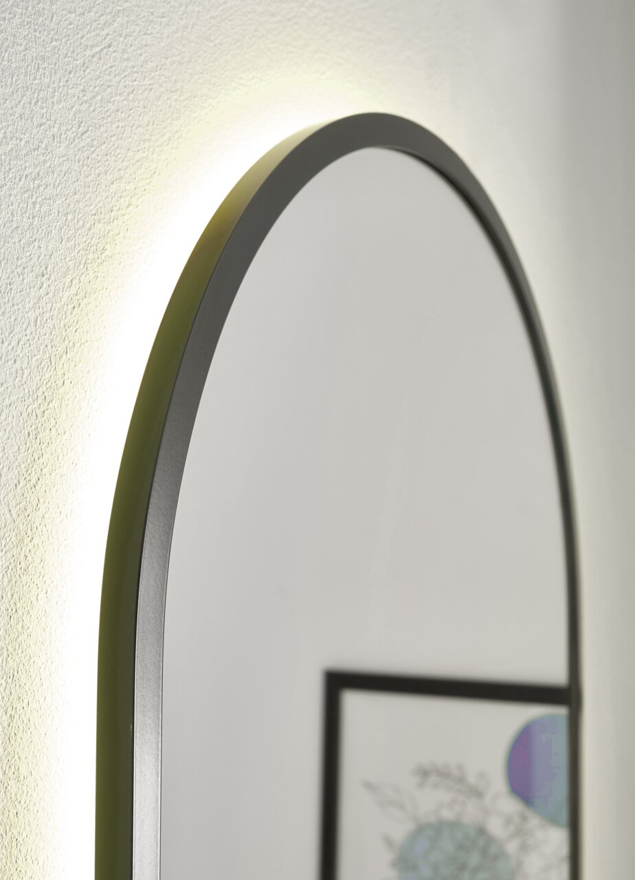 Nahaufnahme eines ovalen Spiegels mit schwarzem Rahmen und Hintergrundbeleuchtung, seitliche Perspektive