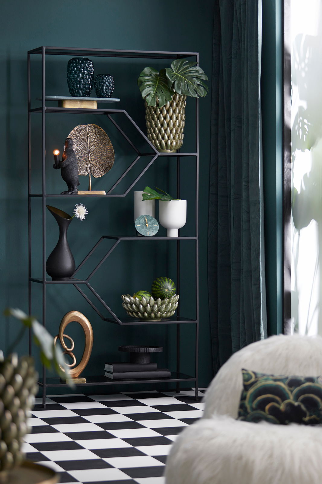 Regal mit dekorativen Objekten, darunter eine Tischleuchte in Form eines Affen, der eine Glühbirne hält. Perspektive von vorne.