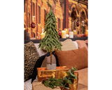 Kleiner künstlicher Weihnachtsbaum auf einem Ständer, umgeben von goldenen Geschenken und Dekorationen, in einer gemütlichen Wohnzimmeratmosphäre. Perspektive: Frontalansicht.
