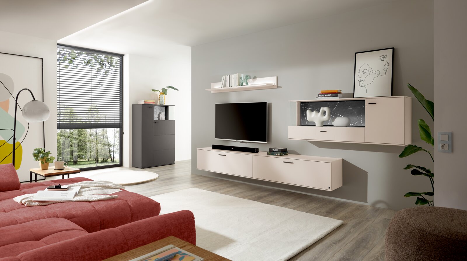 Modernes Wohnzimmer mit wandmontierter TV-Wohnwand in Beige/Creme (Lowboard und Hängeschrank mit Vitrine), Fernseher und Soundbar, aufgenommen in frontaler leicht schräger Perspektive von links.