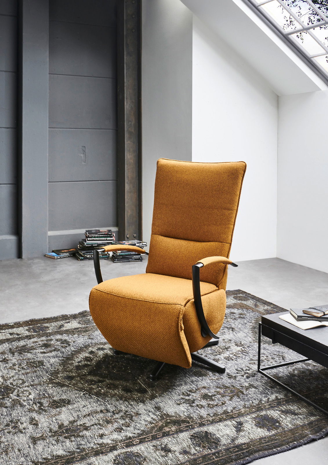 Moderner, drehbarer Relaxsessel in senfgelber Farbe, seitliche Perspektive, auf einem gemusterten Teppich in einem stilvollen Raum platziert.