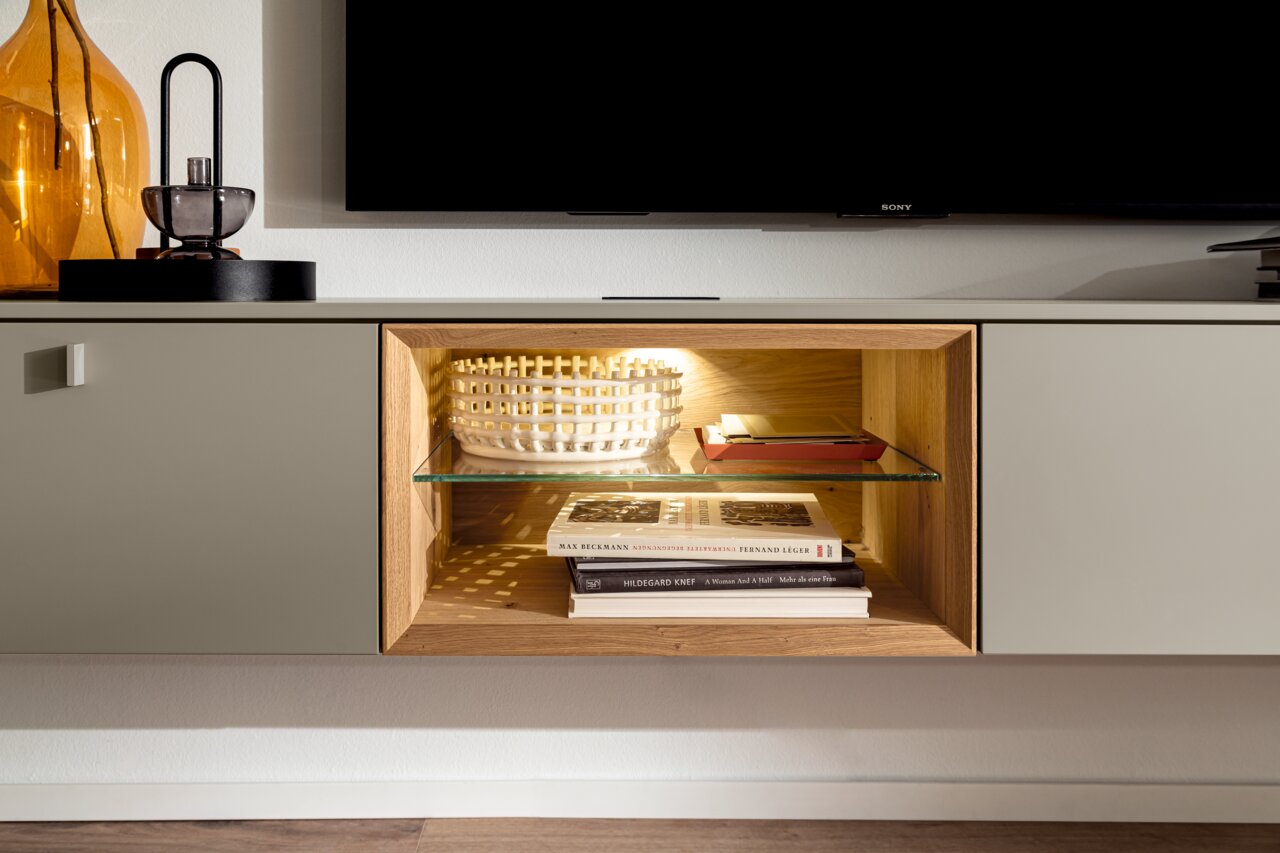 Moderne Wandkombination mit integriertem Regal, Glasboden und Beleuchtung, seitliche Perspektive