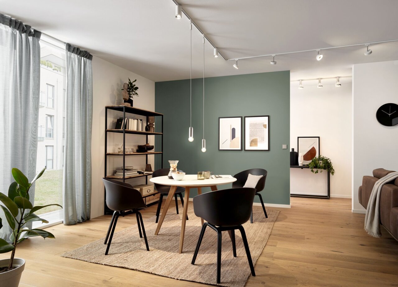 PAULMANN Basispendel URAIL Moderne Esszimmeransicht mit Paulmann Basispendel URAIL, das von der Decke über einem runden Tisch hängt. Die Perspektive zeigt den Raum von der Seite mit Blick auf den Tisch und die Pendelleuchten.