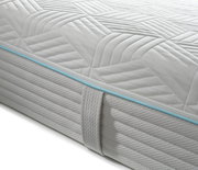 Nahaufnahme einer Gel-Kaltschaummatratze mit gestepptem Bezug und blauer Zierleiste, seitliche Perspektive.