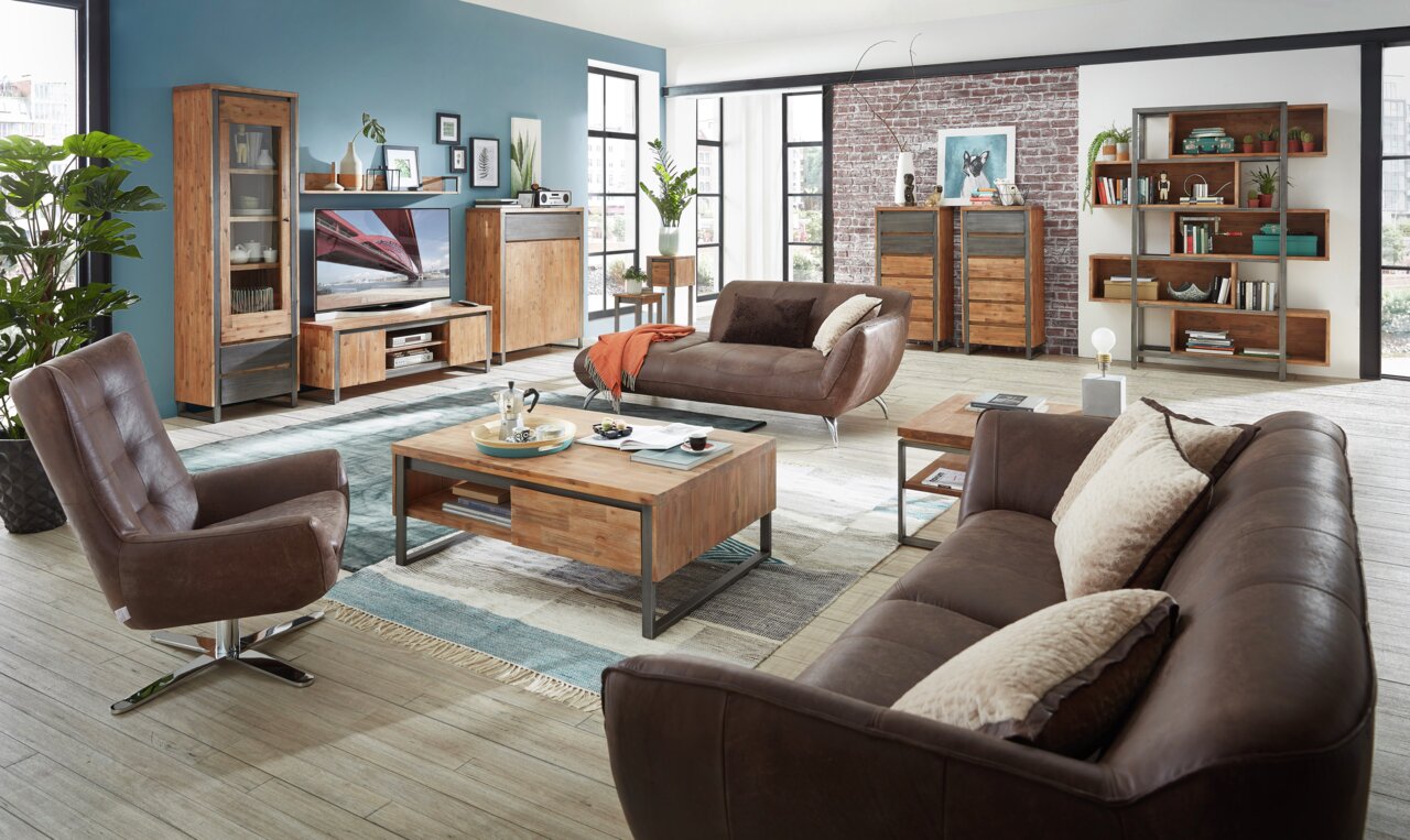 Moderner Wohnraum mit einem braunen Drehsessel im Vordergrund, umgeben von Holzmöbeln und einem gemütlichen Sofa, aus der Perspektive des Wohnzimmers.