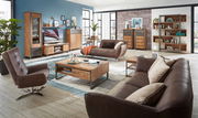Moderner Wohnraum mit einem braunen Drehsessel im Vordergrund, umgeben von Holzmöbeln und einem gemütlichen Sofa, aus der Perspektive des Wohnzimmers.