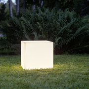 Leuchtender, würfelförmiger Outdoor-Lichtwürfel in warmweiß auf einer Rasenfläche vor Farnen im Garten, Perspektive: frontale Ansicht auf Augenhöhe