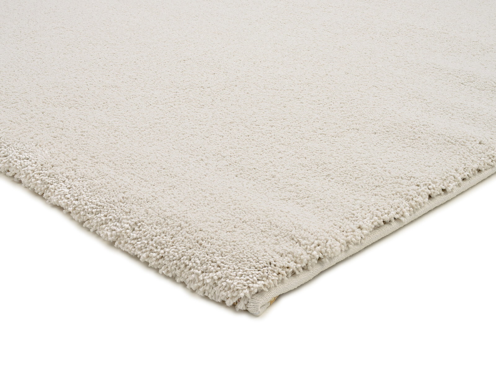 Nahaufnahme eines cremefarbenen Uni-Teppichs mit weicher, flauschiger Textur, von der Seite fotografiert.