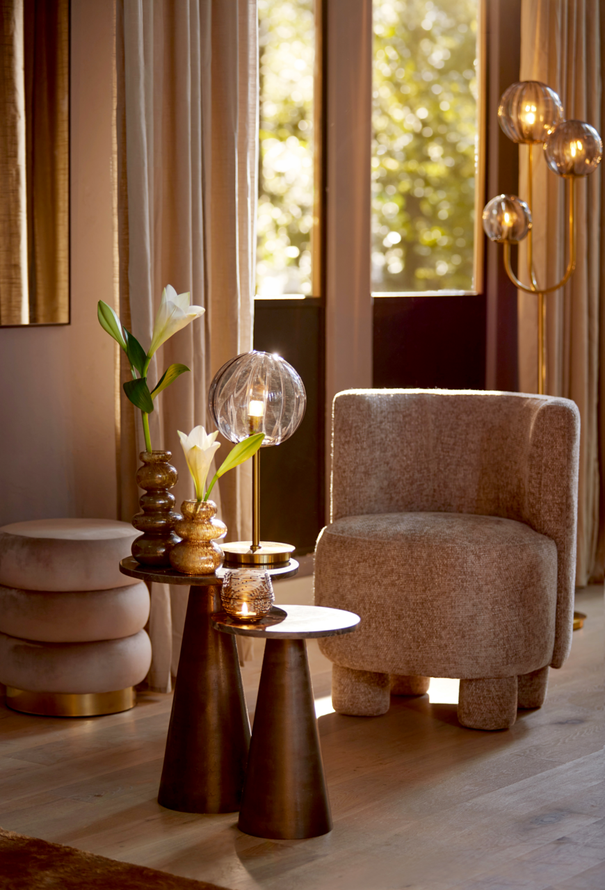 Gemütlicher Sessel in einem stilvollen Wohnzimmer, seitliche Perspektive, umgeben von eleganten Dekorationen und warmem Licht.