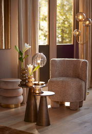 Gemütlicher Sessel in einem stilvollen Wohnzimmer, seitliche Perspektive, umgeben von eleganten Dekorationen und warmem Licht.