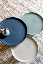 Draufsicht auf drei runde Beistelltische in verschiedenen Farben mit gerillter Oberfläche, dekoriert mit einer kleinen Vase.