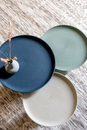 Bovenaanzicht van drie ronde bijzettafeltjes in verschillende kleuren met een geribbeld oppervlak, versierd met een klein vaasje.