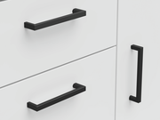 Nahaufnahme einer weißen Kommode mit schwarzen Griffen, seitliche Perspektive