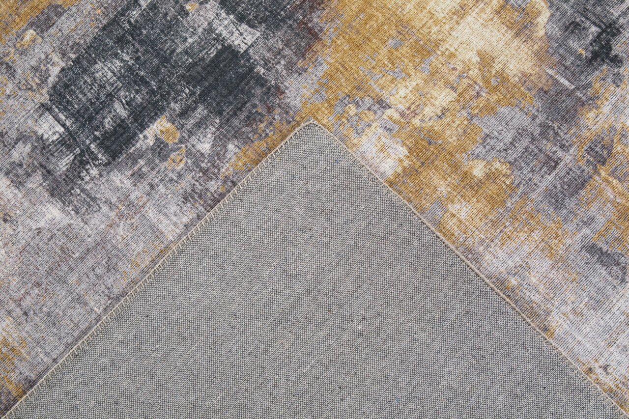 Tapijt met een abstract patroon in grijze en gouden tinten, detailfoto van de voor- en achterkant.