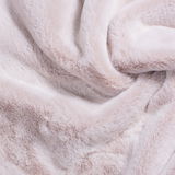 Nahaufnahme einer weichen, flauschigen Decke in hellem Beige, die in Falten gelegt ist.