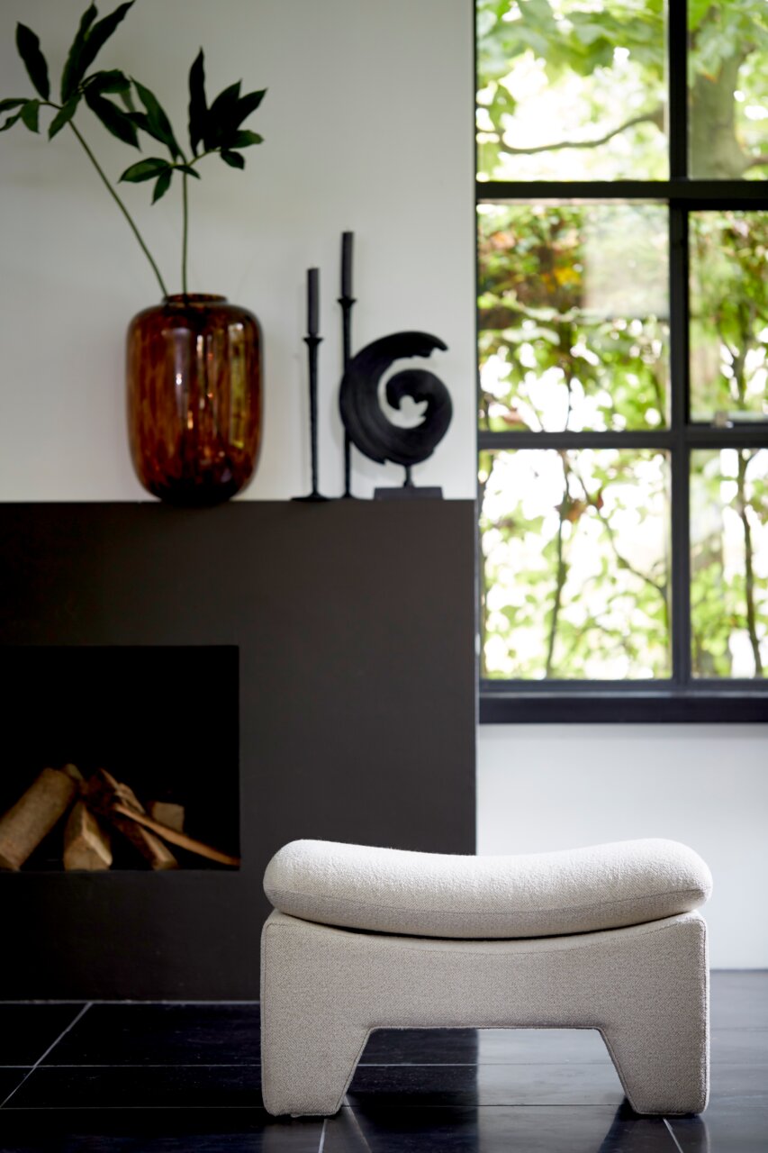 Light&Living Sitzpuff DASHA Moderner Sitzpuff in heller Farbe, frontal vor einem Kamin und einem Fenster mit Blick ins Grüne.