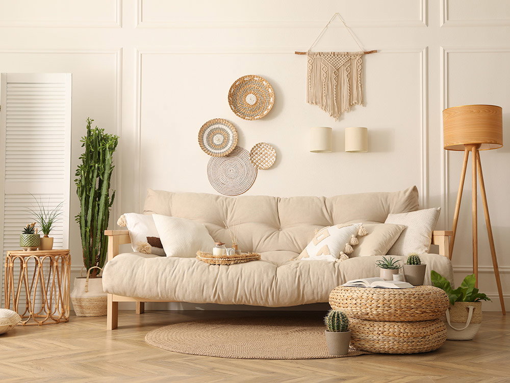 Een gezellige woonkamer met een beige bank, rieten decoraties aan de muur en kamerplanten.