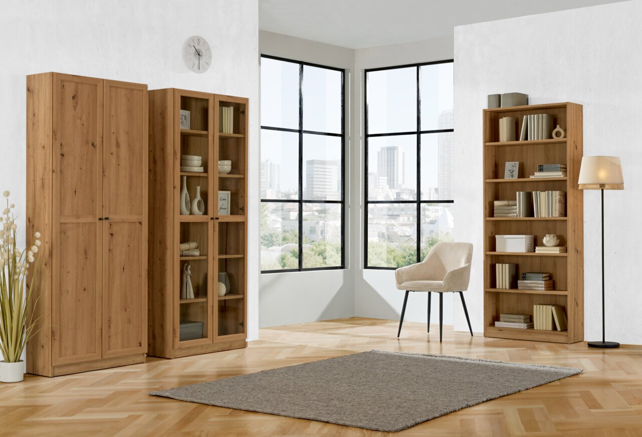 Wohnzimmer mit drei Holzregalen, einem Sessel und einer Stehlampe vor großen Fenstern mit Stadtblick, Perspektive von vorne.