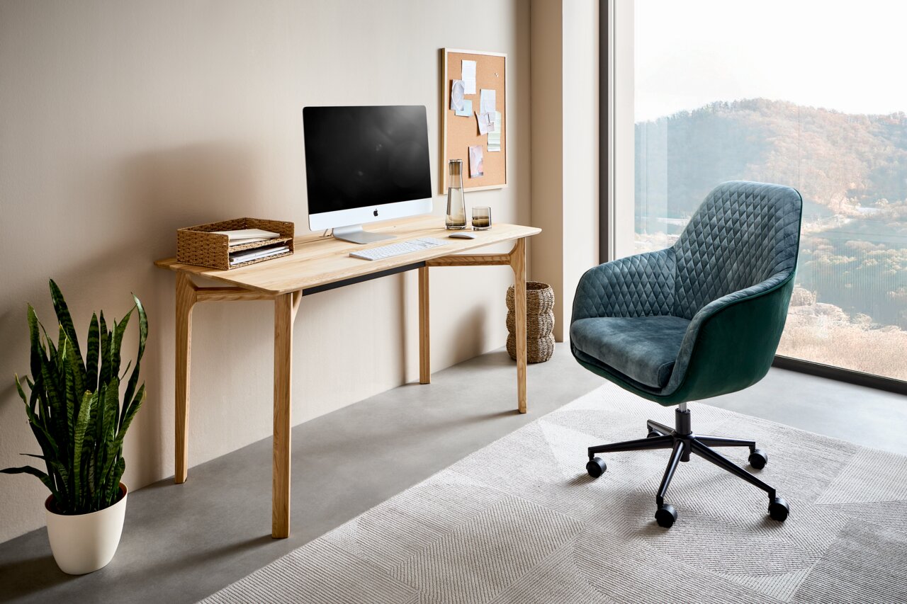 Linea Natura Schreibtisch SOPHIA Moderner Schreibtisch aus Holz mit Computer, Pflanzen und einem bequemen Bürostuhl in einem hellen Raum mit Blick auf die Landschaft, seitliche Perspektive.
