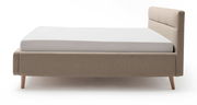 Seitliche Ansicht eines modernen Polsterbetts in Beige mit Holzfüßen und gepolstertem Kopfteil.