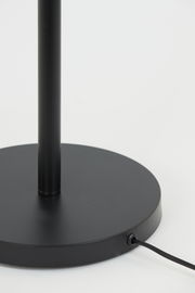 Nahaufnahme des schwarzen Sockels einer Stehleuchte mit Kabelanschluss, seitliche Perspektive.