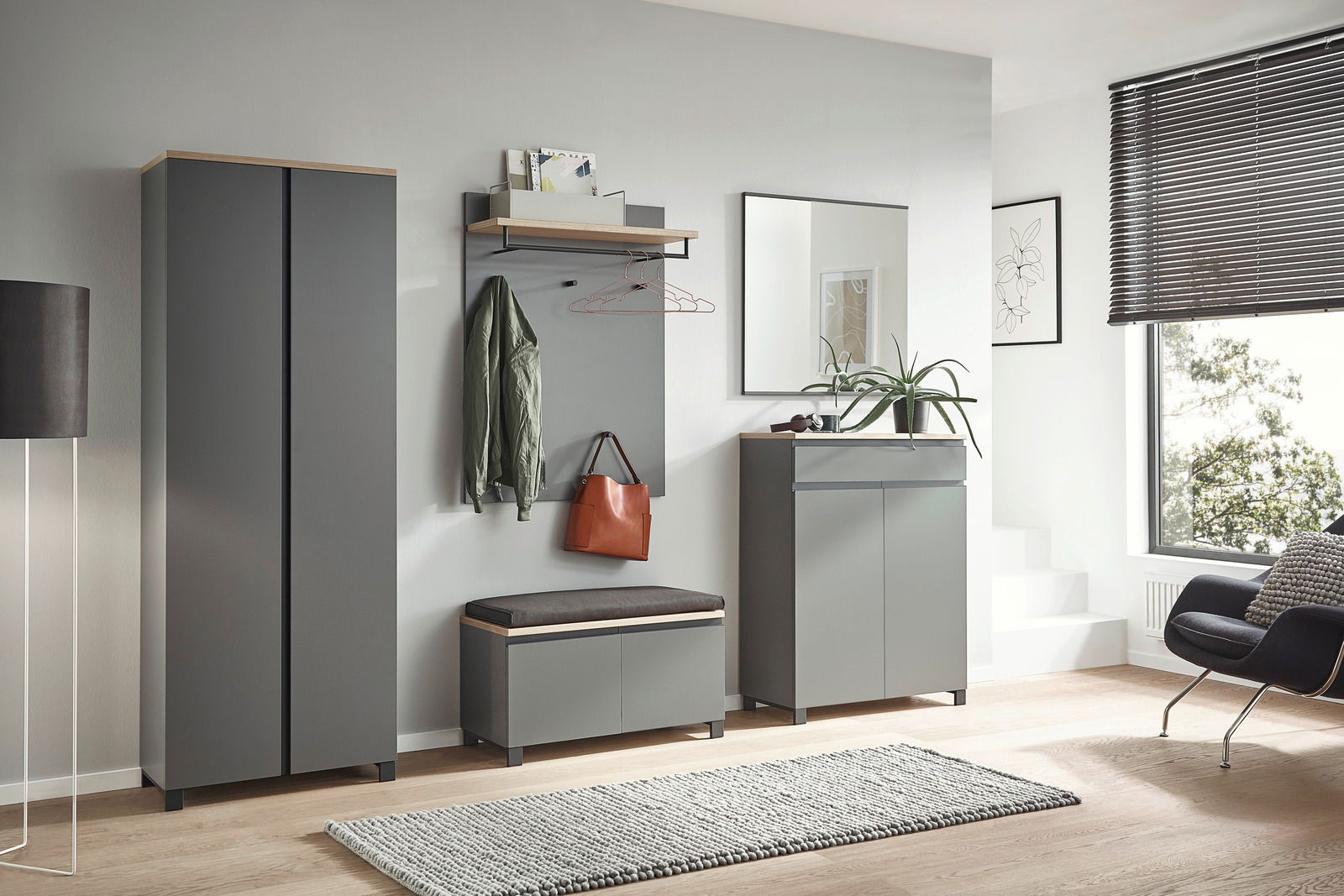 Moderne Garderobeneinrichtung in Grau mit Schuhschrank, Garderobenpaneel, Sitzbank und Spiegel, seitliche Perspektive.