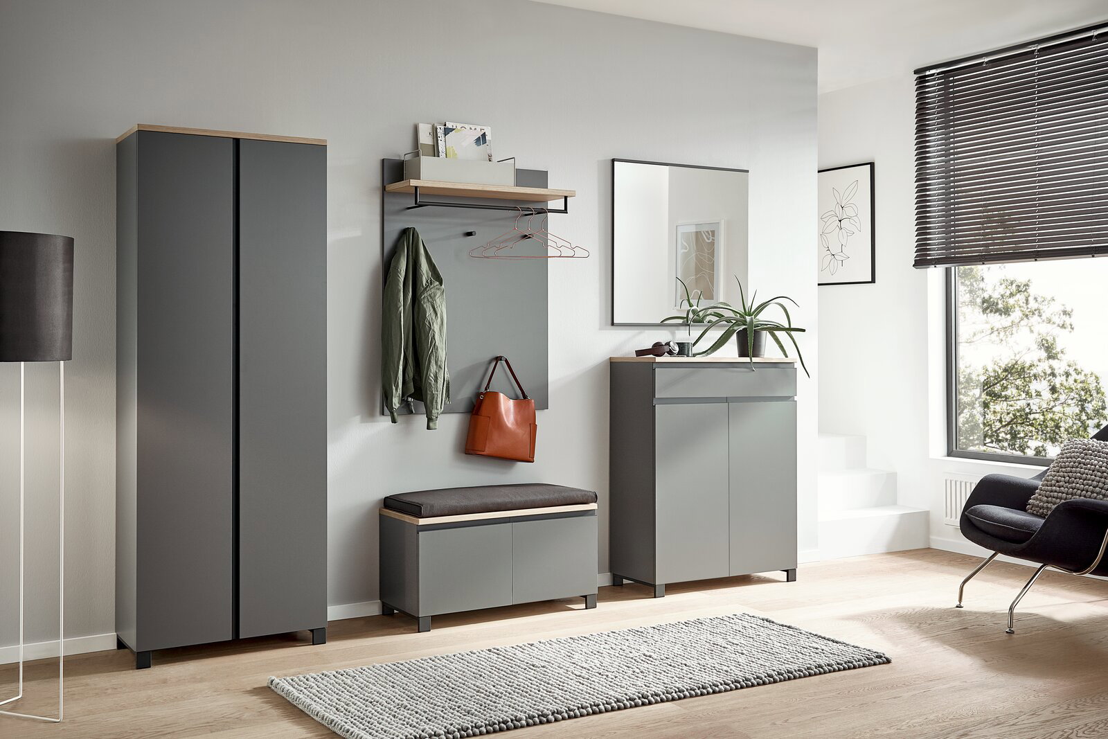Moderne Garderobeneinrichtung in Grau mit Schuhschrank, Garderobenpaneel, Sitzbank und Spiegel, seitliche Perspektive.