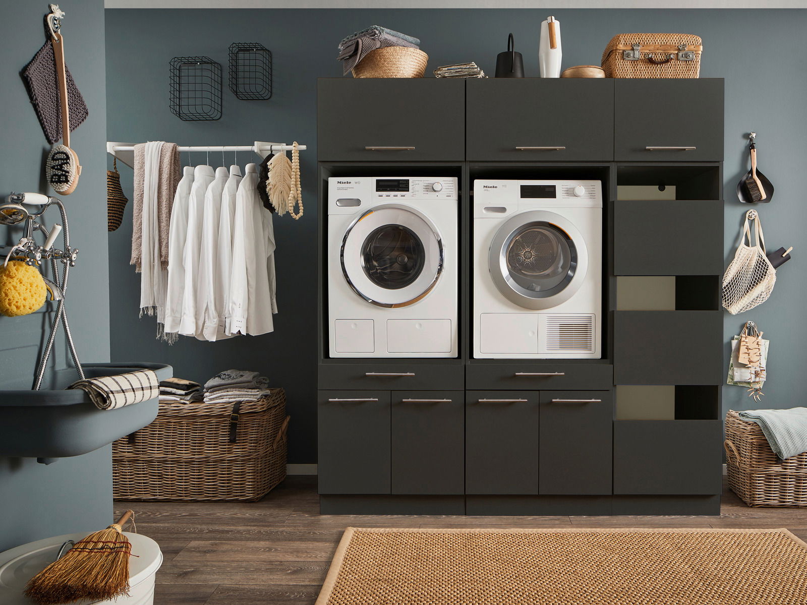 Moderne Hauswirtschaftsraum-Kombination mit Waschmaschine und Trockner, umgeben von Schränken und Regalen, frontal betrachtet.