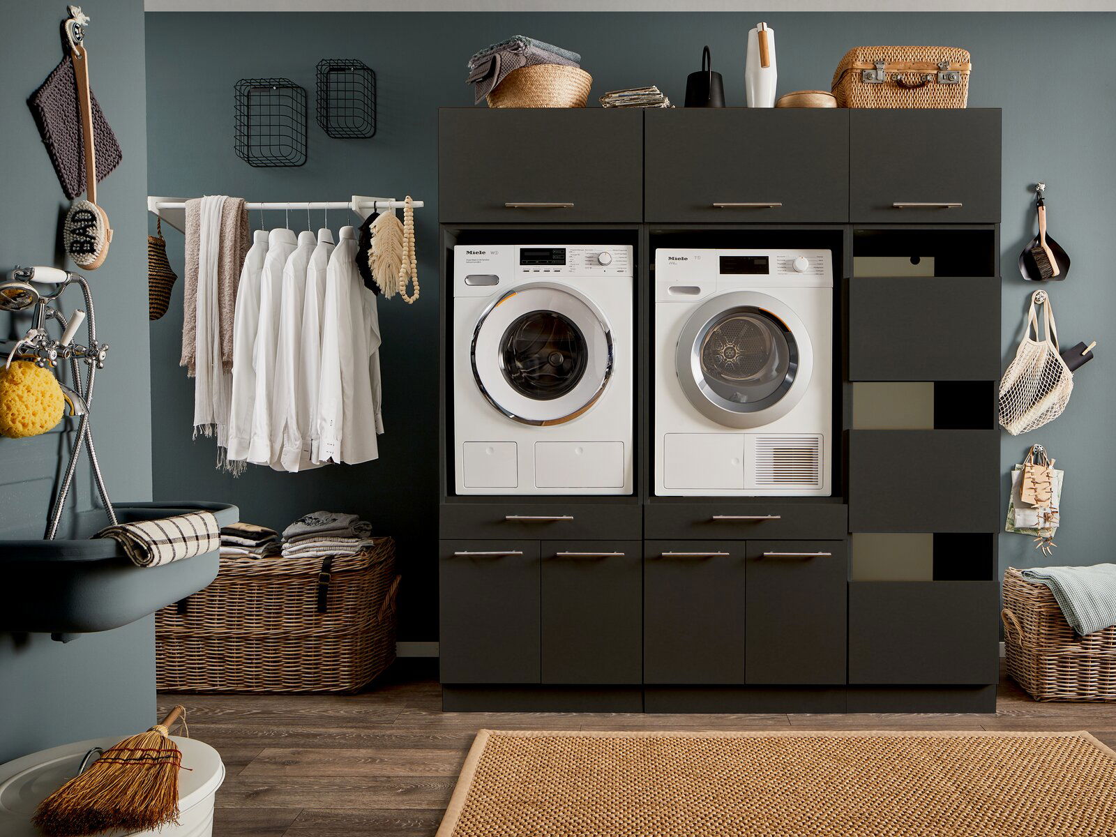 Moderne Hauswirtschaftsraum-Kombination mit Waschmaschine und Trockner, umgeben von Schränken und Regalen, frontal betrachtet.
