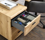 Rollcontainer aus Holz mit geöffneter Schublade, gefüllt mit Büroartikeln, aus der Perspektive von schräg oben.