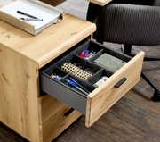 Rollcontainer aus Holz mit geöffneter Schublade, gefüllt mit Büroartikeln, aus der Perspektive von schräg oben.