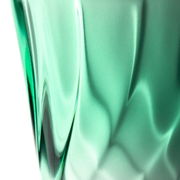 Nahaufnahme eines grünen Trinkglases mit verdrehtem Design, seitliche Perspektive