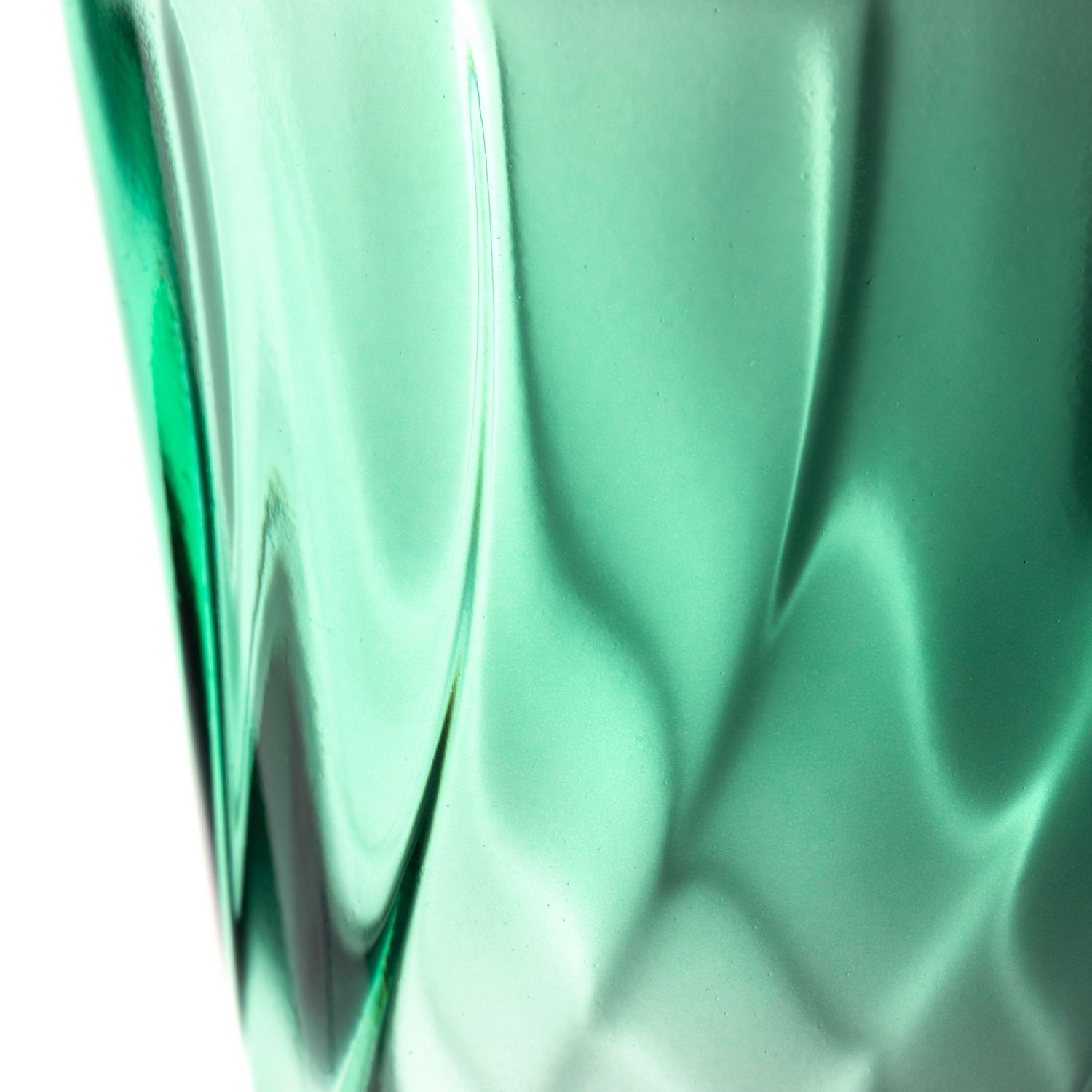 Nahaufnahme eines grünen Trinkglases mit verdrehtem Design, seitliche Perspektive