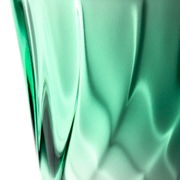 Nahaufnahme eines grünen Trinkglases mit verdrehtem Design, seitliche Perspektive