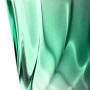 Nahaufnahme eines grünen Trinkglases mit verdrehtem Design, seitliche Perspektive