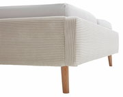 Nahaufnahme eines Polsterbetts mit geripptem, beigem Stoffbezug und Holzbeinen, seitliche Perspektive.